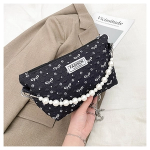 Détail de la trousse de maquillage matelassée noire avec chaîne en perles et nœuds