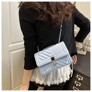 Detail view of light blue chevron quilted crossbody bag with silver chain strap on model