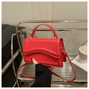 Detail of red leather crossbody bag featuring wave stitching and gold hardware on a display