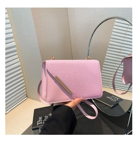 Detail of pink crossbody bag with woven fabric texture and gold metal trim on the flap