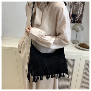 Detail shot of a black bohemian tote bag with long fringe tassels and a slim shoulder strap