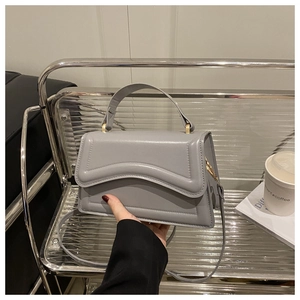 Detail of grey crossbody bag with wave stitching and gold metal ring handle