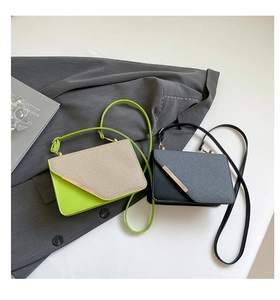 Detail of minimalist shoulder bags in green and black with metal accents on a grey blazer