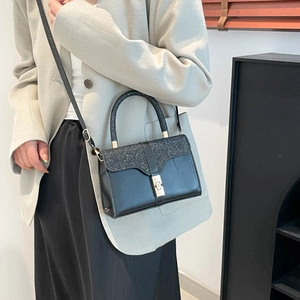Chic black crossbody bag with shimmering sequins and gold hardware shown on a model