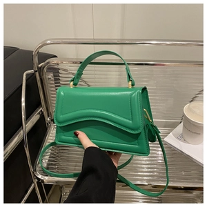 Detail of lime green faux leather bag with curved quilting and gold metal handle links