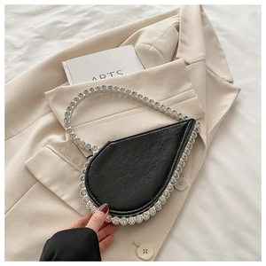 Detail of elegant black heart-shaped clutch bag with sparkling rhinestone edges