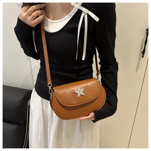 Detail of a brown saddle bag featuring a rhinestone star and textured synthetic leather