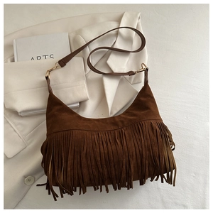 Close-up of a brown suede hobo bag featuring dense bohemian fringes and gold hardware
