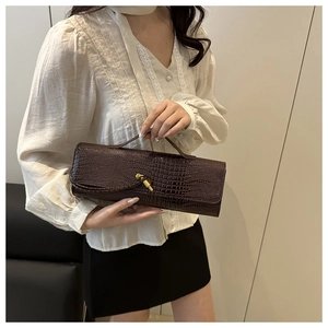 Detail of dark brown crocodile texture bag with vintage gold knot clasp and leather handle