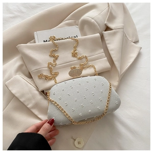 Close-up of light beige hard shell evening bag with point texture and diamond clasp