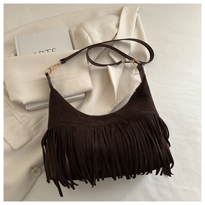 Detail of dark brown suede shoulder bag featuring long bohemian tassels and metal hardware