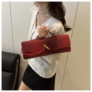 Detail of red crocodile texture baguette bag with golden buckle and sleek handle strap