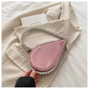 Detail of a pink heart-shaped metallic evening bag with sparkling rhinestone handle and edges