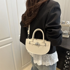 Sac à bandoulière demi-cercle minimaliste crème avec boucle argentée porté par modèle