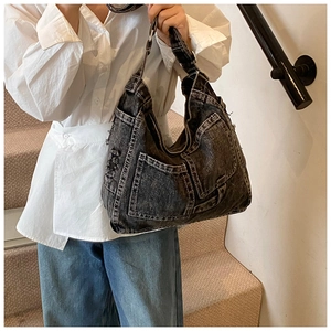 Detail of grey washed denim hobo bag featuring wide straps and spacious side pockets