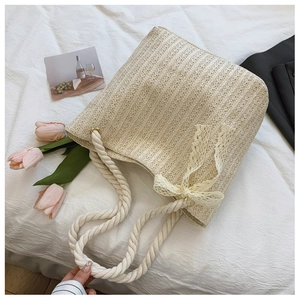 Close-up of cream straw woven tote bag featuring delicate lace bow and cotton rope handles