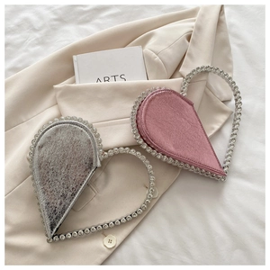 Detail of silver and pink heart-shaped evening bags with rhinestone handles and cracked leather