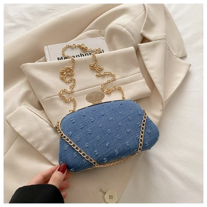 Detail of blue denim clutch bag with sparkling rhinestone clasp and golden chain strap