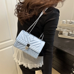 Light blue quilted leather crossbody bag with silver metal chain strap shown on model