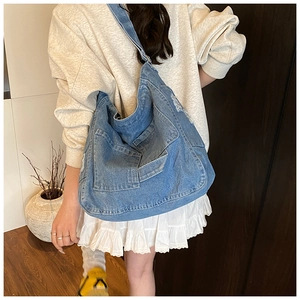 Detail of blue washed denim tote bag with retro distressed texture and utility pockets