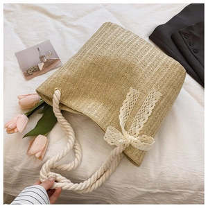 Detailed top view of straw tote bag with cotton rope handles and lace bow decoration