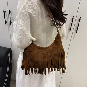 Brown faux suede hobo bag with fringe tassels and gold hardware on female model