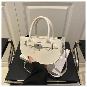 Detail of white semi-circular handbag with silver metal swivel lock and strap detail