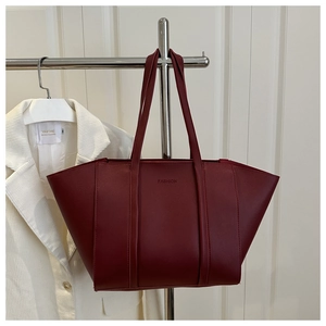 Detail of burgundy leather bucket bag with FASHION embossing hanging on a hanger