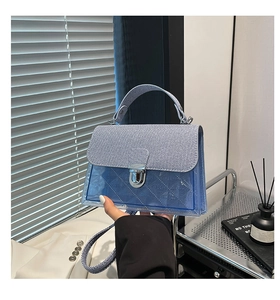 Détail du sac à bandoulière en PVC bleu avec rabat en jean et fermoir rotatif