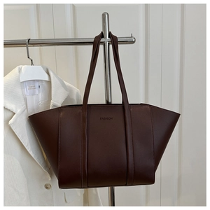 Detail view of large dark brown leather tote bag with embossed fashion text detail