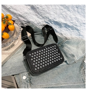 Détail du sac à bandoulière noir à strass et clous argentés sur une veste en jean