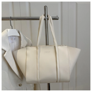 Detail of minimalist cream white tote bag featuring embossed fashion logo and dual straps