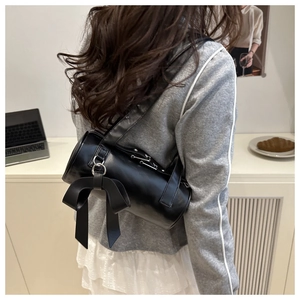 Detail of black cylinder shoulder bag with large bow in a chic balletcore style lifestyle