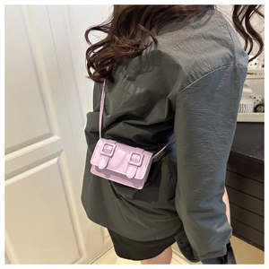Detail of lavender purple crossbody bag with twin decorative buckles on the flap cover