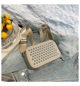 Détail d'un sac bandoulière kaki avec rivets argentés et large sangle en tissu chic