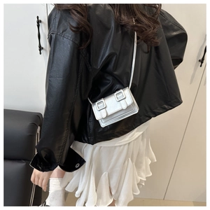 Detail of silver mini crossbody bag with double buckle decor on black leather jacket outfit
