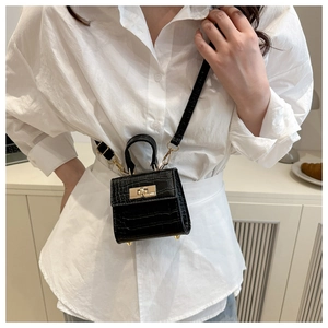 Detail of micro black crocodile pattern handbag with gold hardware on white shirt