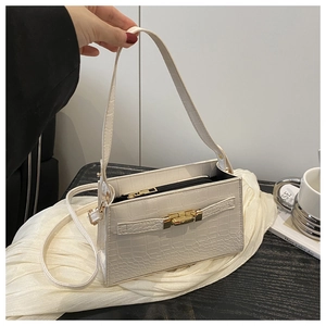 Detailed view of white crocodile pattern baguette bag with a golden twist lock closure