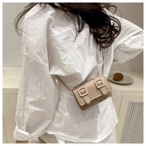 Minimalist beige PU leather crossbody bag worn by a model in a cozy indoor setting