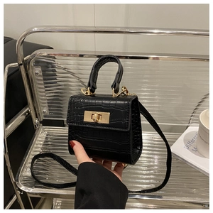 Close-up of black crocodile texture square bag with gold twist lock and shoulder strap