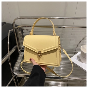 Vue détaillée d'un sac à main jaune pâle avec fermoir tournant doré sur un support fixe