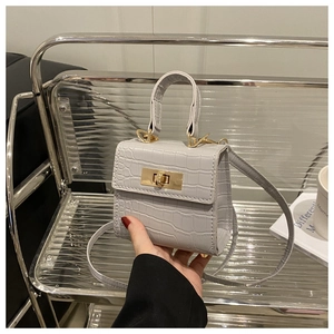 Detail of grey crocodile pattern mini handbag with gold twist lock and top handle