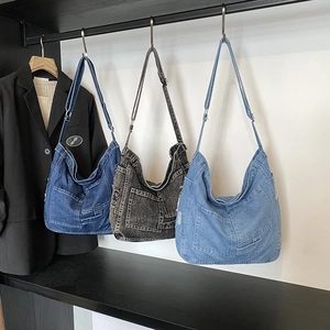 Three washed denim messenger bags in dark blue, black, and light blue with wide straps