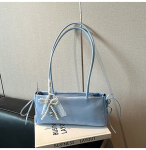 Detail of light blue shoulder bag with pearl bow pendant and delicate white lace ribbon