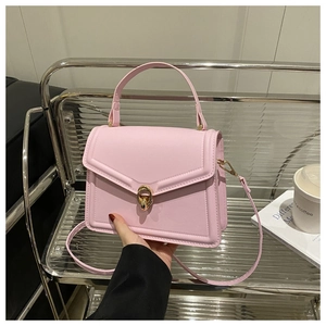 Détail du sac en cuir rose clair avec fermoir rotatif doré et poignée sur le dessus