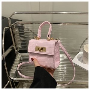 Close-up of pink faux crocodile texture mini bag featuring a gold twist lock and handle