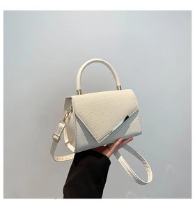 Detail showing white leather handbag with beige woven texture flap and silver metal trim