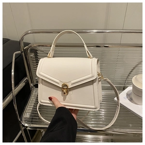 Détail du sac à main blanc structuré avec fermoir rotatif doré et texture en cuir lisse