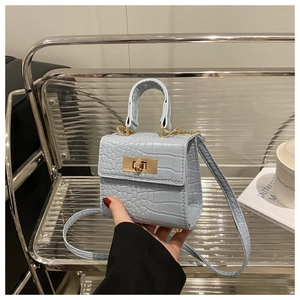 Detail of light blue croc-embossed mini handbag with a gold-tone rotating clasp and handle