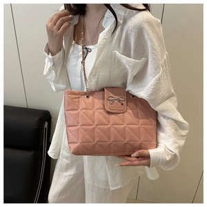 Détail du sac cabas rose matelassé avec nœud argenté et bandoulière en chaîne métal